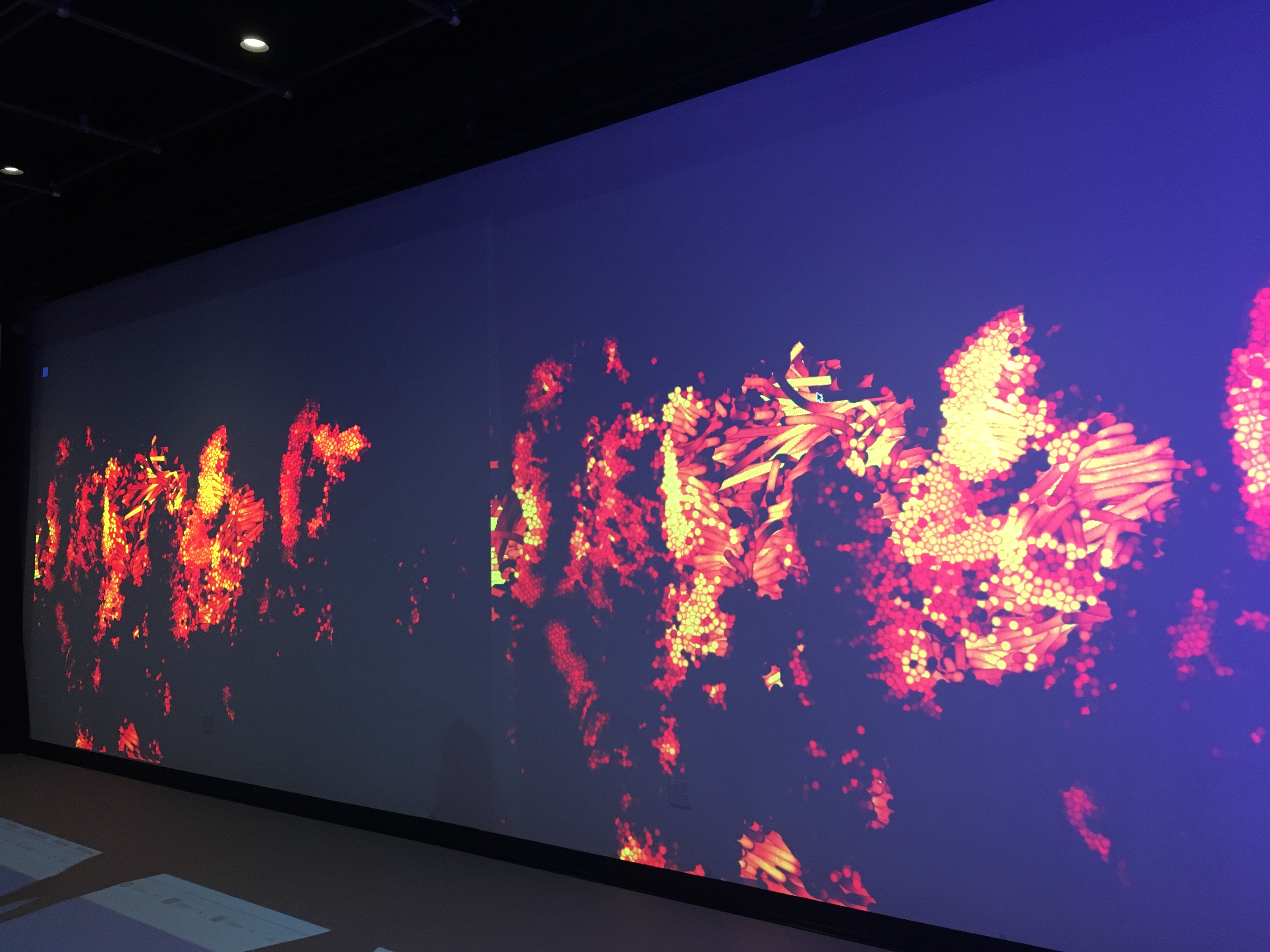 A wall of the Movement Lab, with a visualization resembling a heat map -- dots of bright yellow orange and red, all coming together to form vague bodylike shapes.