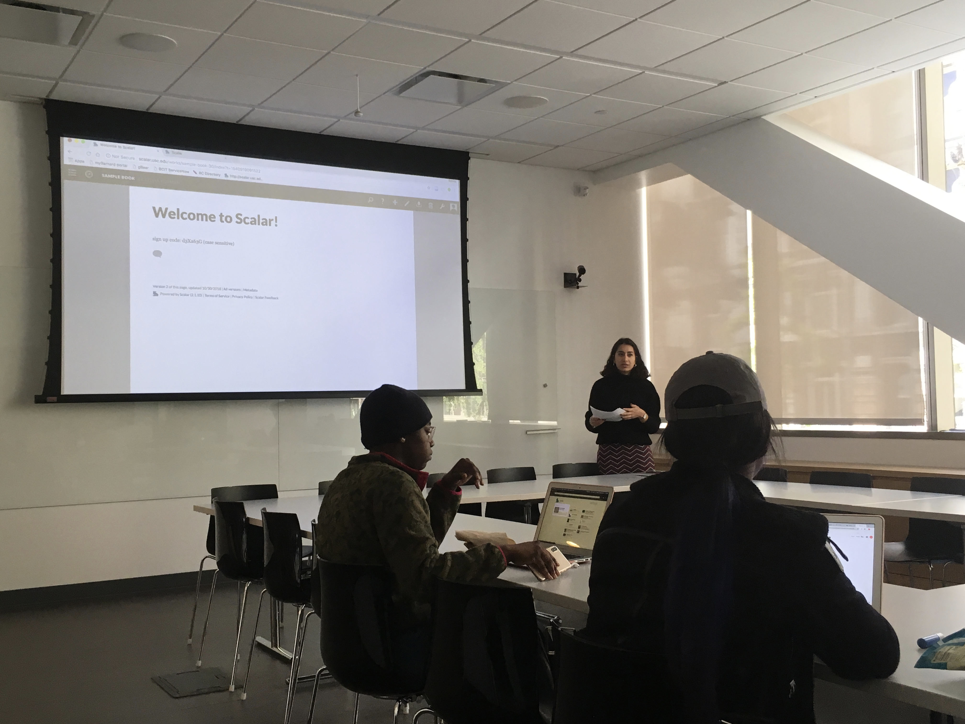Digital Scholarship Librarian Madiha Choksi lectures in front of a screen that says Welcome to Scalar!
